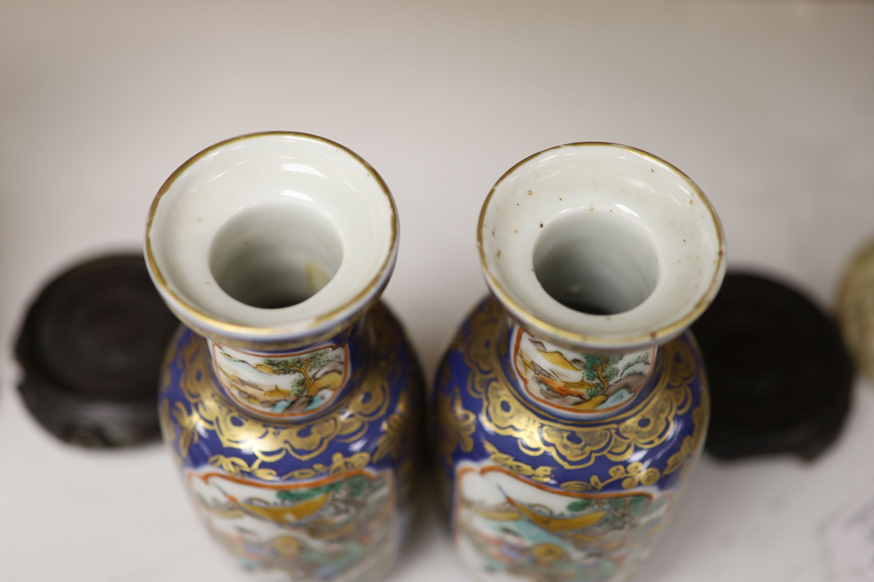 A pair of Chinese Kangxi style blue-ground vases, late 19th century decorated with panels of warriors and heightened in gilt, on carved hardwood stands, height 18cm excluding stand